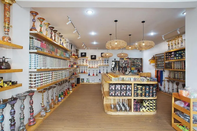 A bright retail store featuring wooden shelves fully stocked with shisha tobacco tubs, hookahs, and accessories. The perfect one-stop shop when figuring out where to smoke & buy Tangiers in Bali.